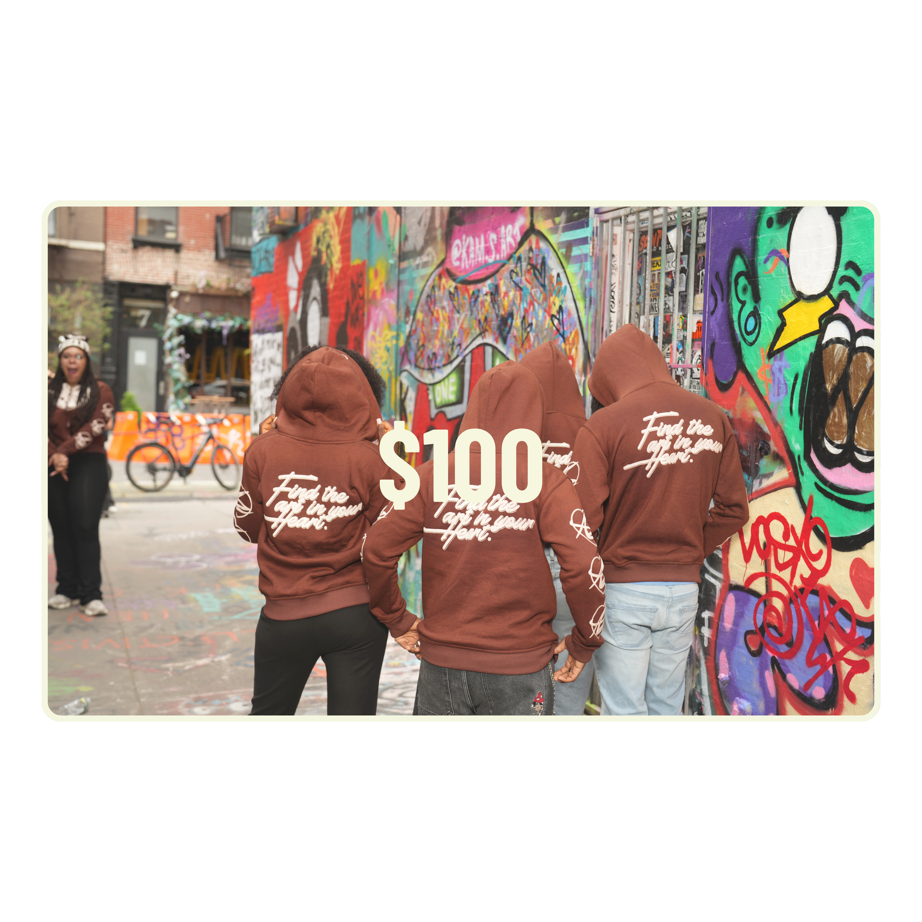 Three people wearing brown hoodies with text in front of a colorful graffiti wall.