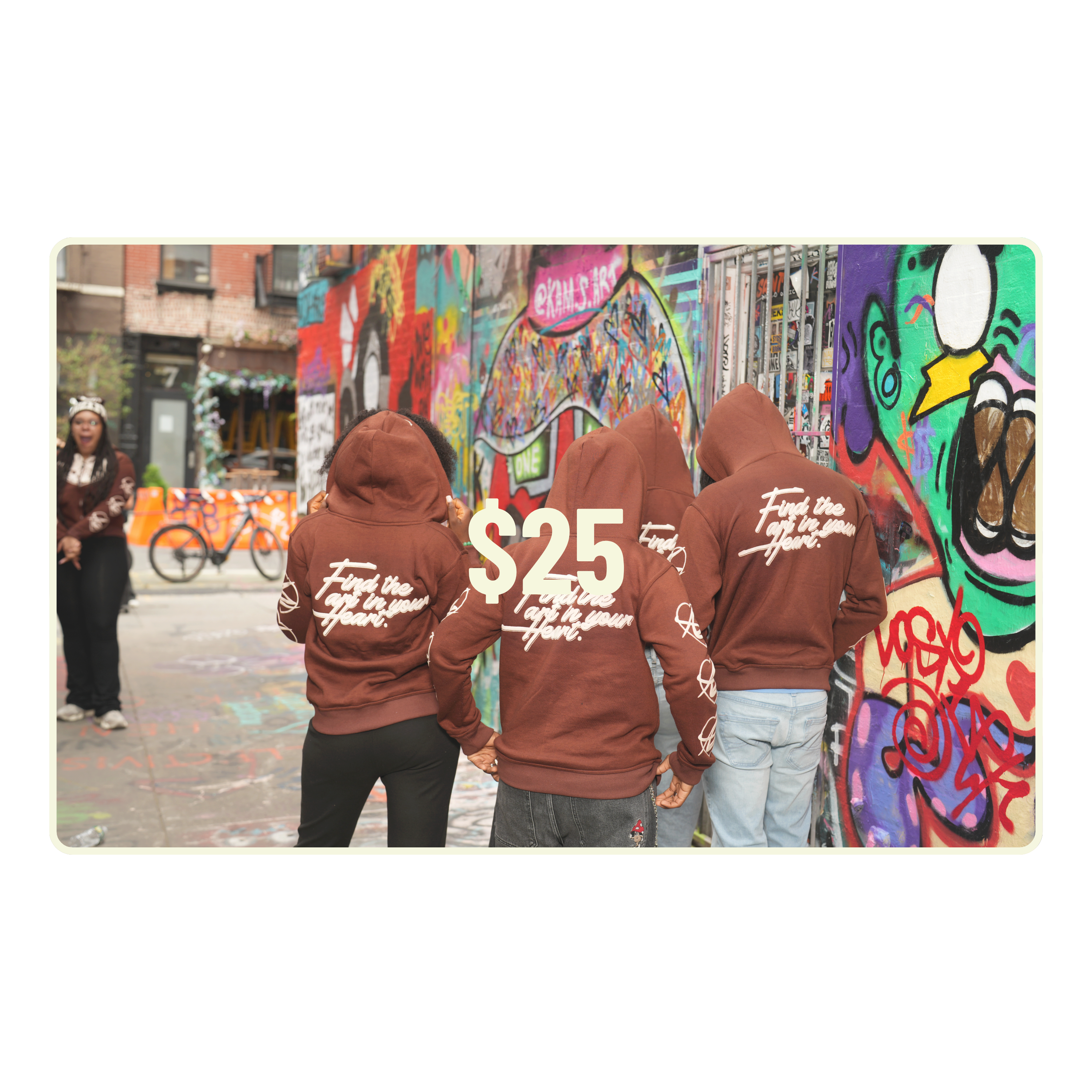 Three people wearing brown hoodies with text in front of a colorful graffiti wall.