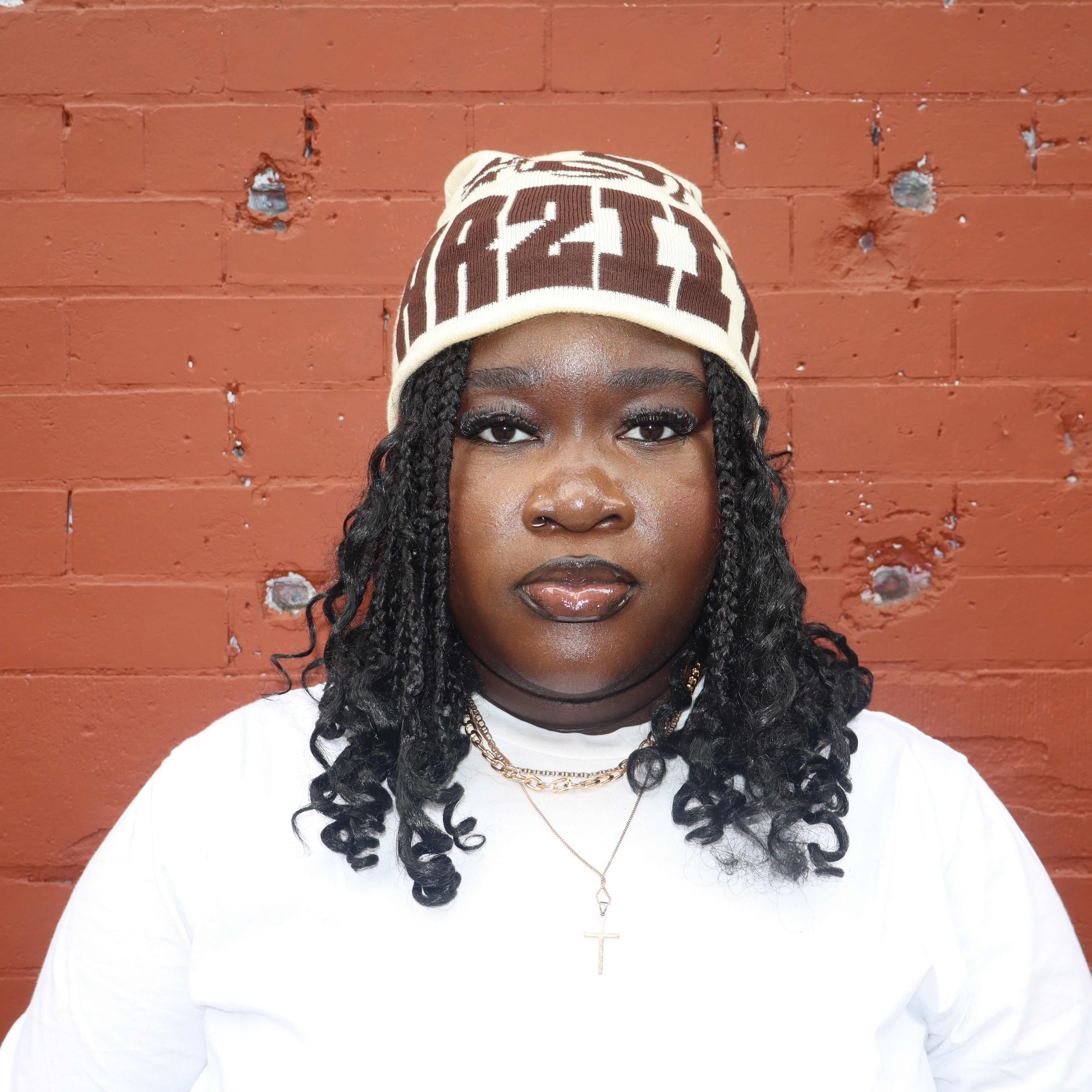 Person wearing a cap and white shirt against a red brick wall